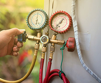 Hand adjusting HVAC pressure gauges on a service unit, representing maintenance and repair services by Tri-Star Heating & Air.
